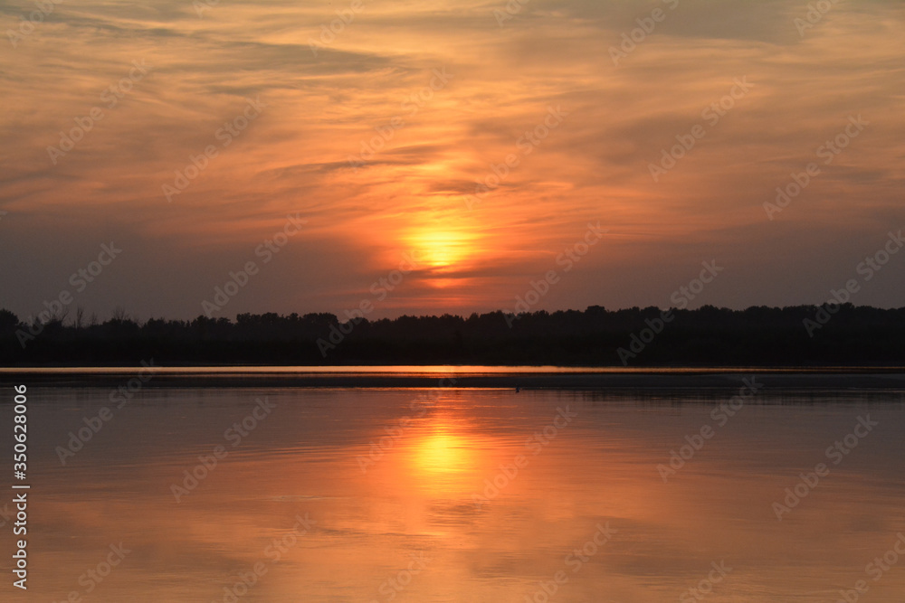 Beautiful sunset on the Volga river. 
The sun is reflected in the river. Russia. Golden background.