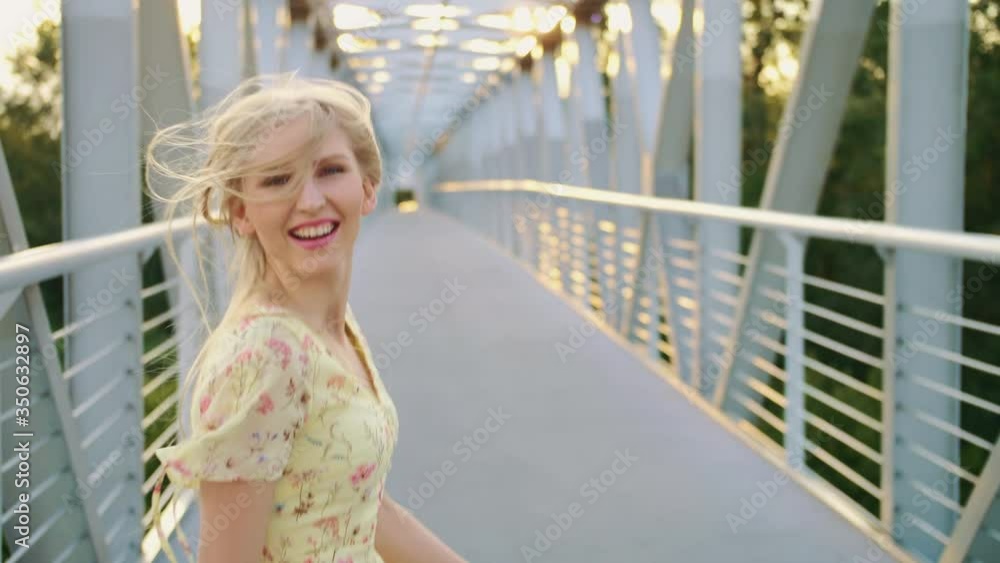 Woman looking back on bridge. Pretty blonde woman looking back at camera while running on bridge with wavy hair. 4k Woman looking back on bridge. Pretty blonde woman looking back at camera while running on bridge with wavy hair. 4k