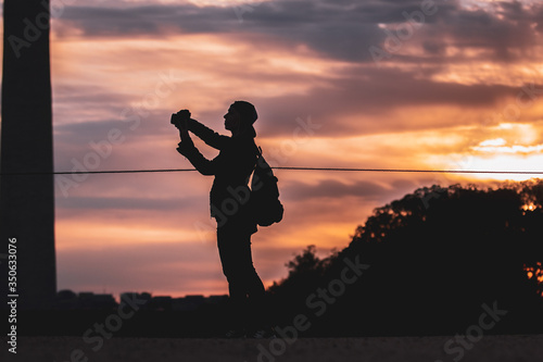 A woman photographs the sunset on the National Mall