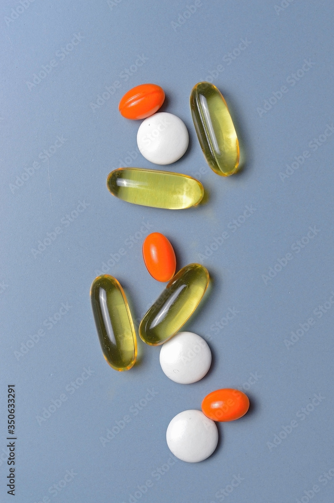 multi-colored pills and vitamins in capsules on a gray background. top view multi-colored pills and vitamins in capsules on a gray background. top view