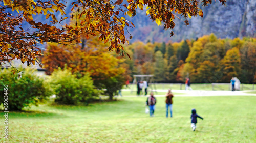 Leaves changing color in autumn with blurred happy family spending time together outdoor and forest background.
