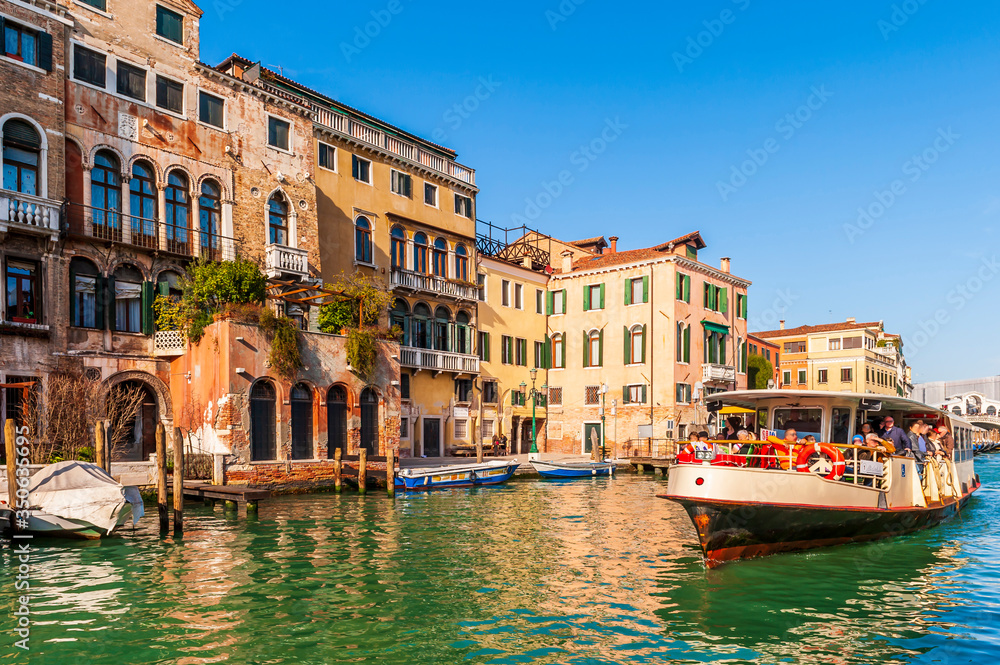 Medieval facades on the Grand Canal and a vaporetto in Venice in Veneto, Italy - obrazy, fototapety, plakaty 