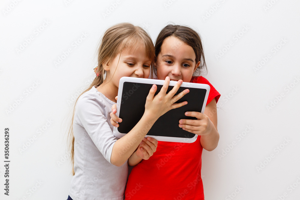 Little girls playing on a tablet computing device sitting on the floor Little girls playing on a tablet computing device sitting on the floor