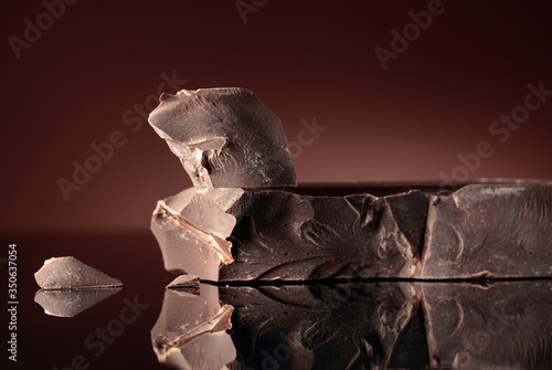 Large piece of dark bitter chocolate on a black reflective background.