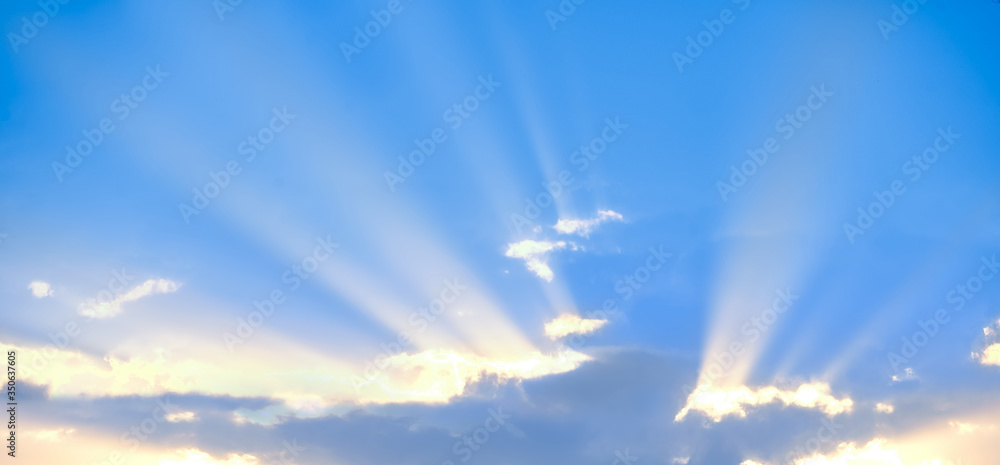 Horizontal shot of background of sun rays over clouds.