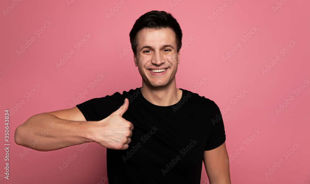 Hitting like. Close-up photo of a happy male in a black t-shirt, who is looking in the camera with a big smile and showing thumbs up. Hitting like. Close-up photo of a happy male in a black t-shirt, who is looking in the camera with a big smile and showing thumbs up.