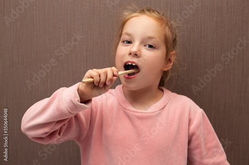 Redhead girl child brushes her teeth.