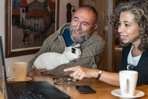 couple petting a cat and drinking coffee with a laptop photo