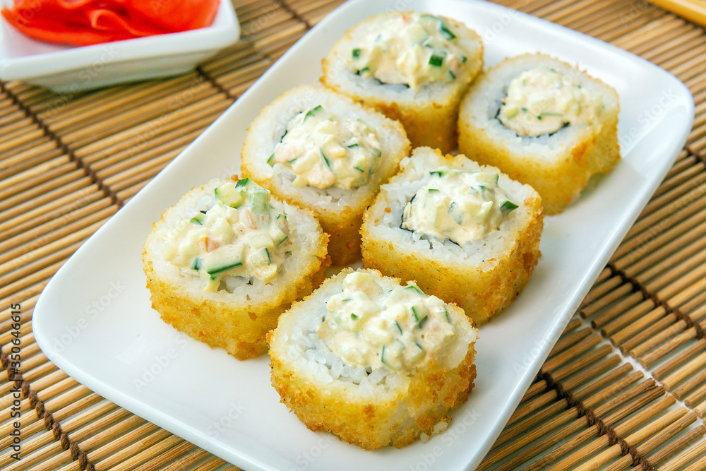 Tempura Maki Sushi-Deep Fried Roll made of Crab Meat, with cucumber. Served on Wooden Plate. sushi Japanese cuisine menu