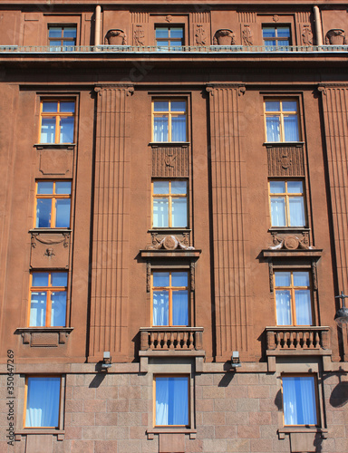 Historic building architecture with classic style simple windows in row. Multi-story old house facade, dark brown colored walls with windows. Residential city house facade, close up exterior detais photo