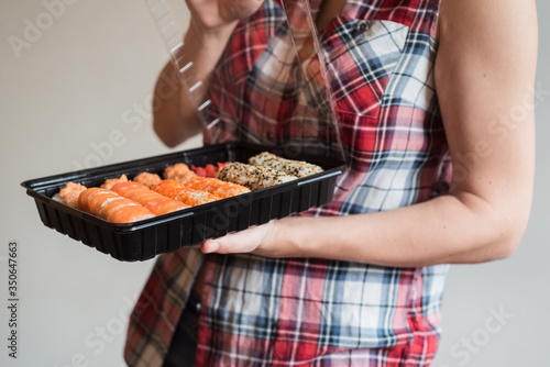 A large set of delicious sushi rolls in the hands of a girl. The concept of delivering food from a restaurant