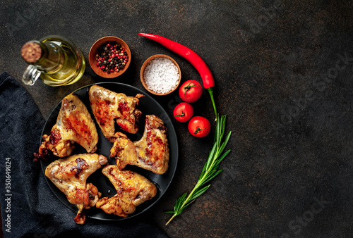 Grilled chicken wings on a plate with spices on a stone background with copy space for your text