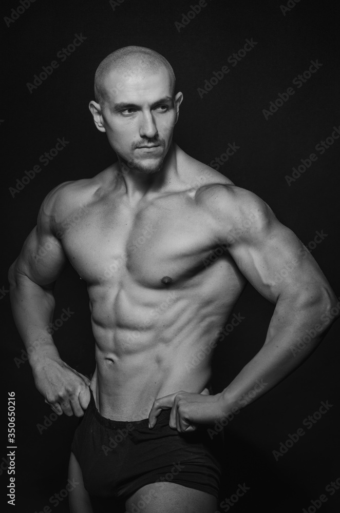 Fototapeta premium Sporty guy posing in the Studio on the background. Sports, beauty, black and white photography
