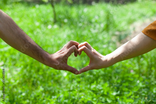 woman and man hand heart on grass background © Alla
