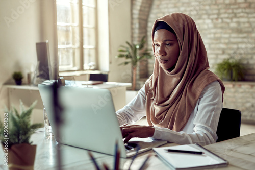 Black Islamic businesswoman working on a computer in the office.