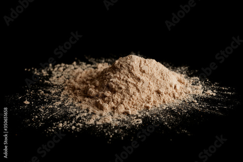 Spilled brown powder looking like unrefined heroin, isolated