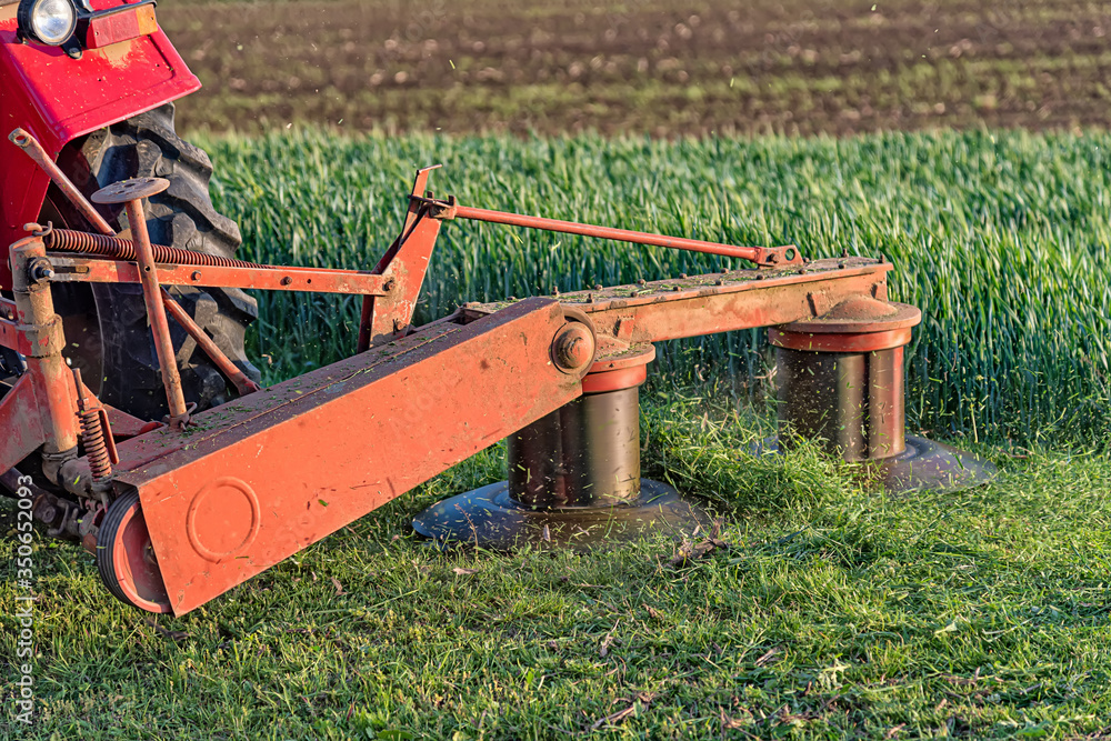 A tractor with implements mower cuts clover. Tractor mowing paddock A tractor with implements mower cuts clover. Tractor mowing paddock