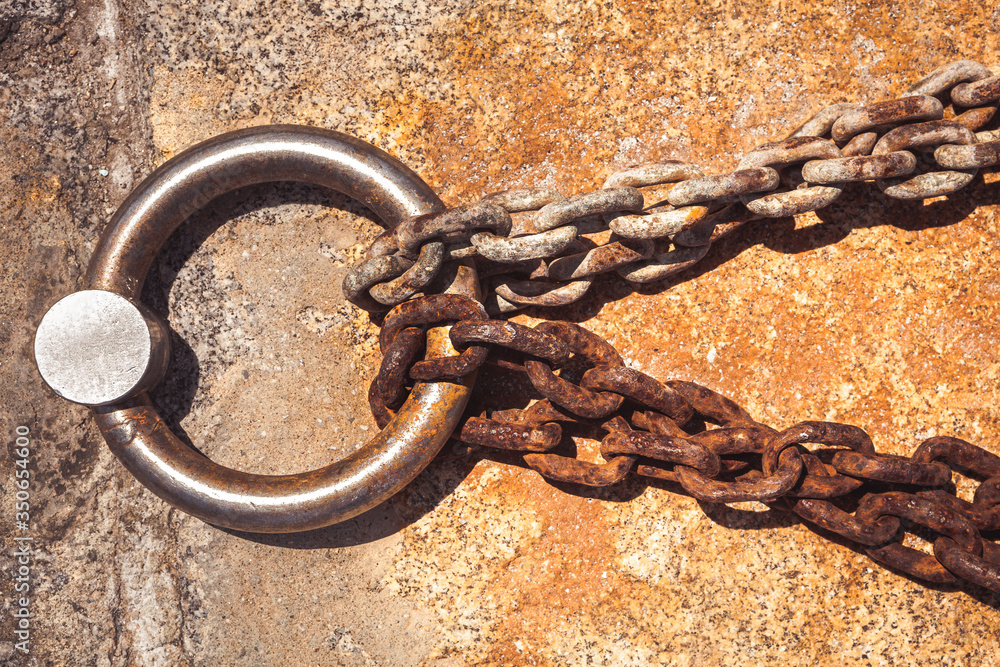 Obraz premium Rusty steel ring and mooring lines in a seaport. Rusty iron chain on the concrete ground.