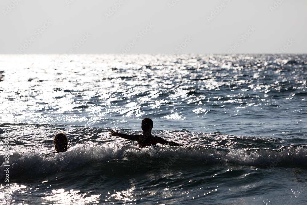 Fototapeta premium Silhouette of people jumping out of the water. Happy people