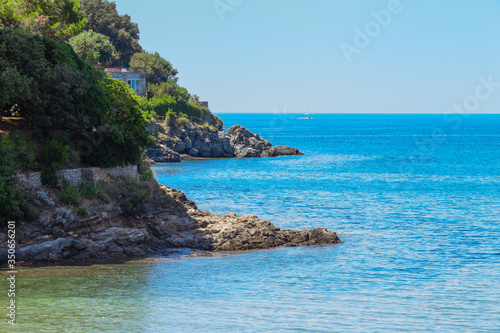 Seashore coastline with cliff and rocks on a mountain slope. Blue sea of the Island of Elba in Italy in the Tuscany region. Crystal clear sea. Mediterranean Sea