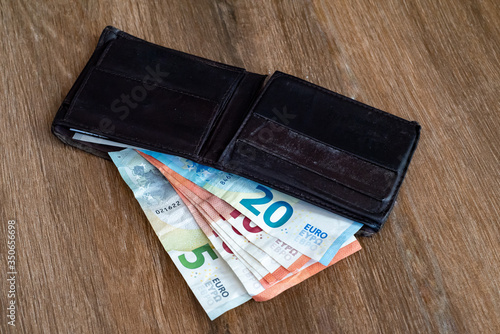 Old shabby wallet with euro money on a wooden background