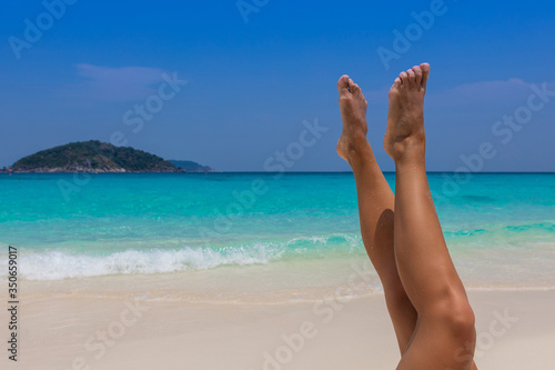 Beautiful woman with legs raised up high in the air. Similan Islands, white sand, blue water.