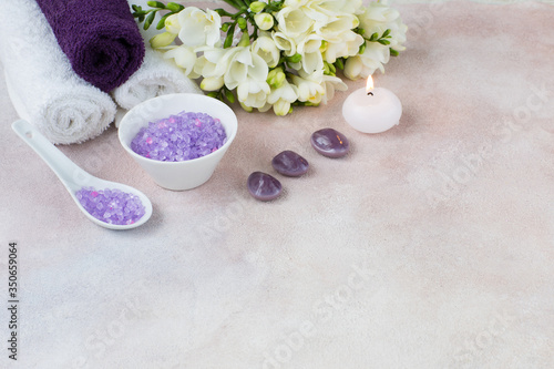 towels, candle, salt, a bouquet of freesia and stones - items for a spa procedure