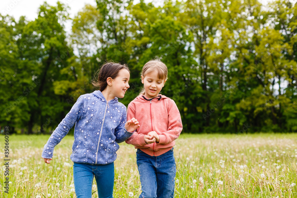 Two sisters hug one another outdoors, happy family