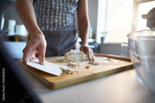 Woman using a dough scraper, making fresh dough at home.