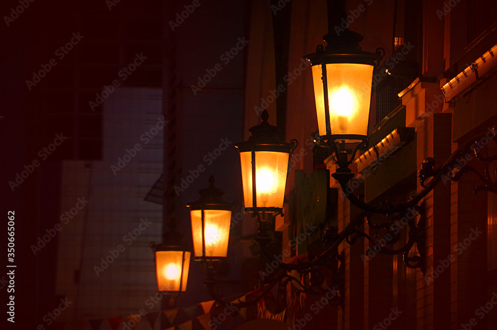 Φωτογραφία Night street view with glowing real gas lanterns on the outdoor wall