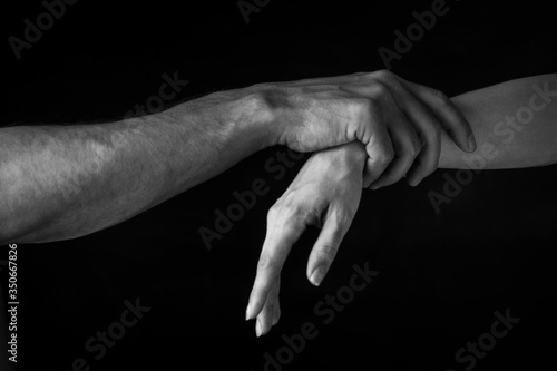 a man holds a woman's wrist against a dark background. close up. black and white photo