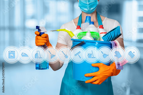 Cleaning lady with cleaning products on blurry background .