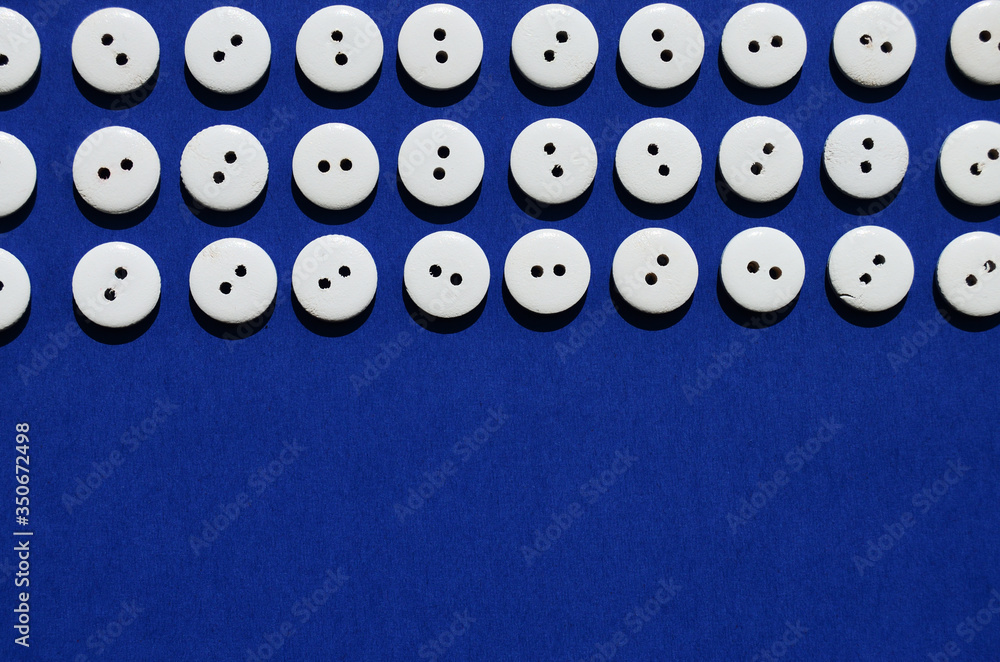 Pattern white wooden buttons on the top edge on a blue background with copy space