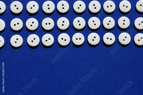 Pattern white wooden buttons on the top edge on a blue background with copy space
