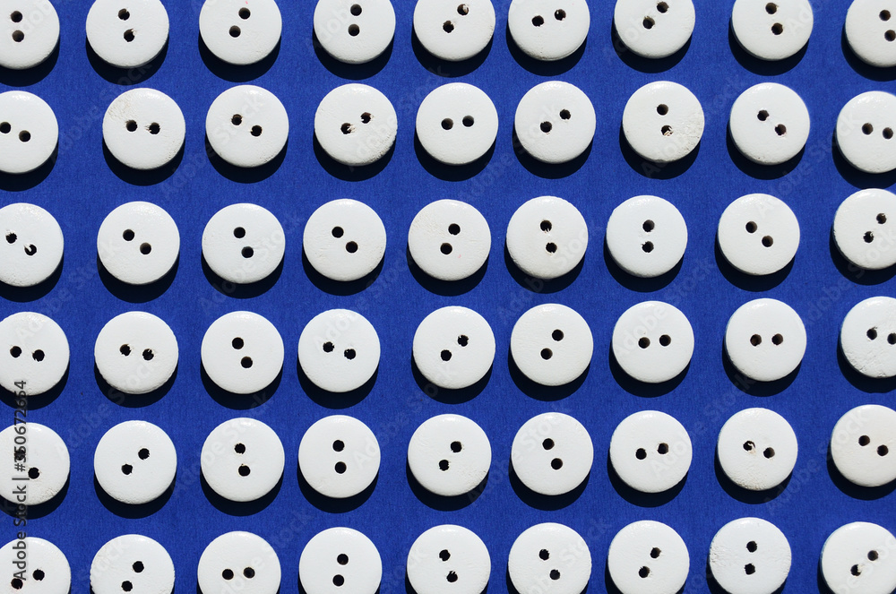 Pattern white wooden buttons on a blue background view from above Pattern white wooden buttons on a blue background view from above