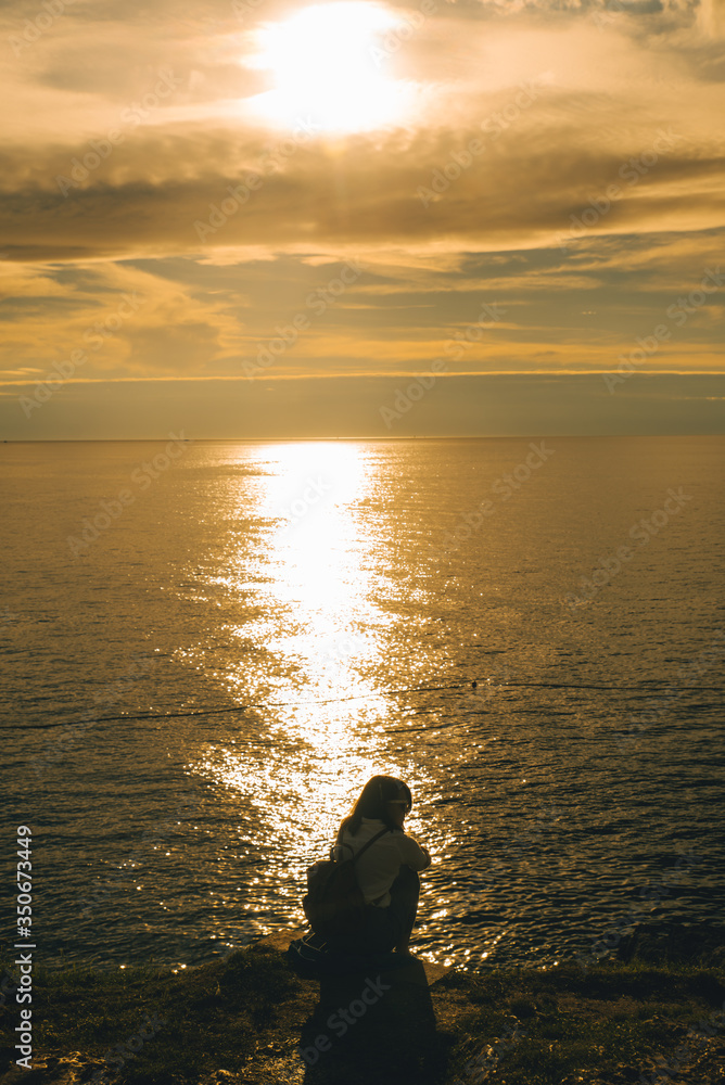 woman sitting at sea beach enjoying the beauty of sunset woman sitting at sea beach enjoying the beauty of sunset