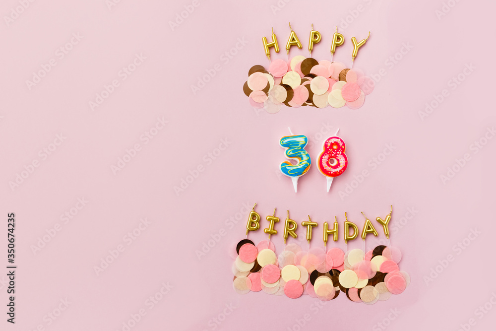 Greeting candles in the form of the number 38 are decorated with pastel confetti on a pink background. Birthday card. Copy space