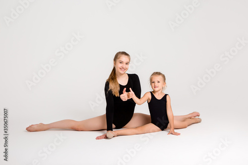 Young girl gymnastics coach deals with little girl student on white background