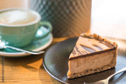 Slice of vegan peanut butter cake in cafe. Green cup with coffee cappuccino photo