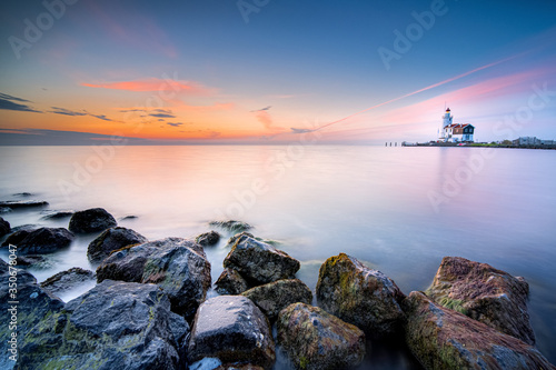 Lighthouse on the Dutch coast near the island of 'marken' during sunrise on a large inland lake photo