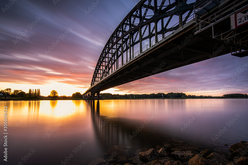 Naklejka premium Striking arch bridge spans the river during the sunrise