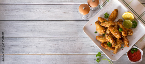 Crispy chicken wings with lemon and sauce. View from above, top view. Copy space photo