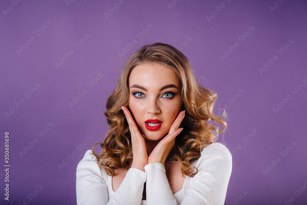 A young beautiful girl shows emotions and smiles in the Studio on a purple background. Girls for advertising A young beautiful girl shows emotions and smiles in the Studio on a purple background. Girls for advertising