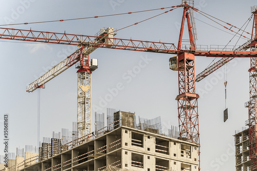 Several cranes have been put to work on the construction of a modern multi-storey residential complex. Concept work for people with the profession of builder. Large construction site. © Anna Shnaider