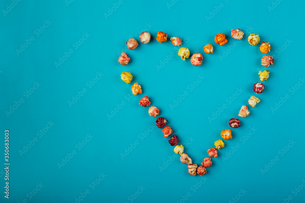 Heart laid out of corn kernels on a blue background.