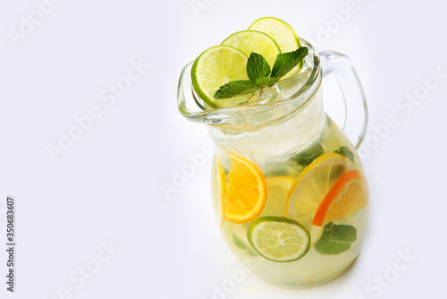 Orange and lime lemonade with mint in a tall glass jug on a white background. An isolated object. Copy space.
