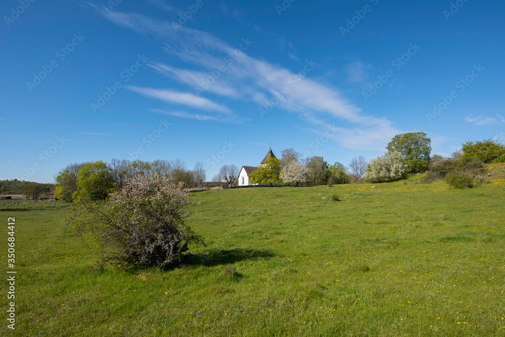 Spring landscape at a old viking tumulus on the island Adelsö and the church Adelsö kyrka close to Stockholm