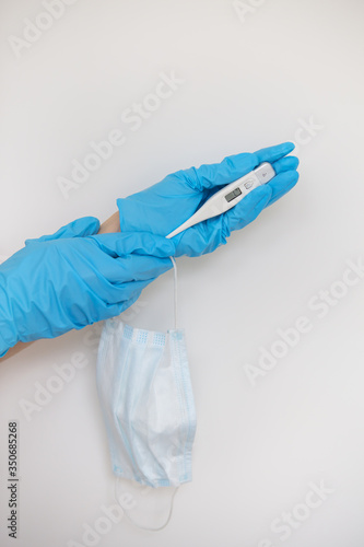 Medic's hand wearing a blue latex glove holding a thermometer