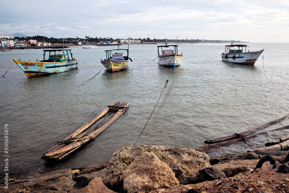 Kanniyakumari, India - September 14, 2013: A bamboo raft, and fishing boats tied along the shore.