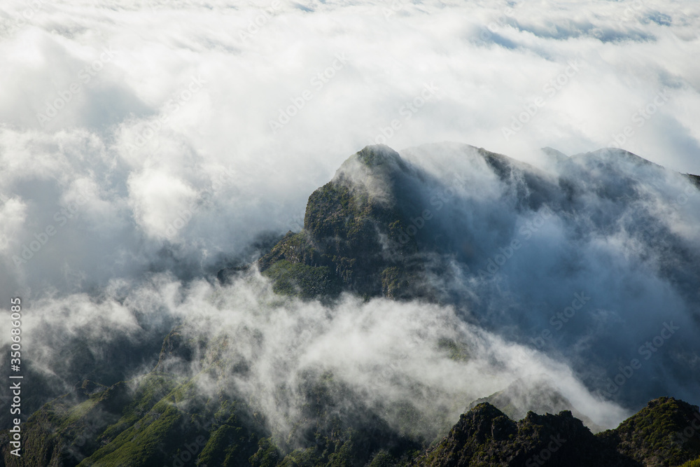 Mountain peak in white clouds, beautiful landscape of Pico Ruivo trekking path in Madeira island, scenic cloudscape view on mountains